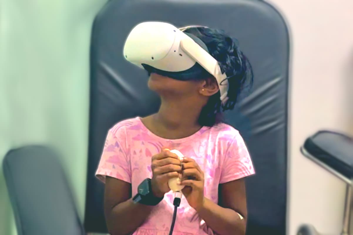 A child wearing the research headset and holding a tactile input while seated